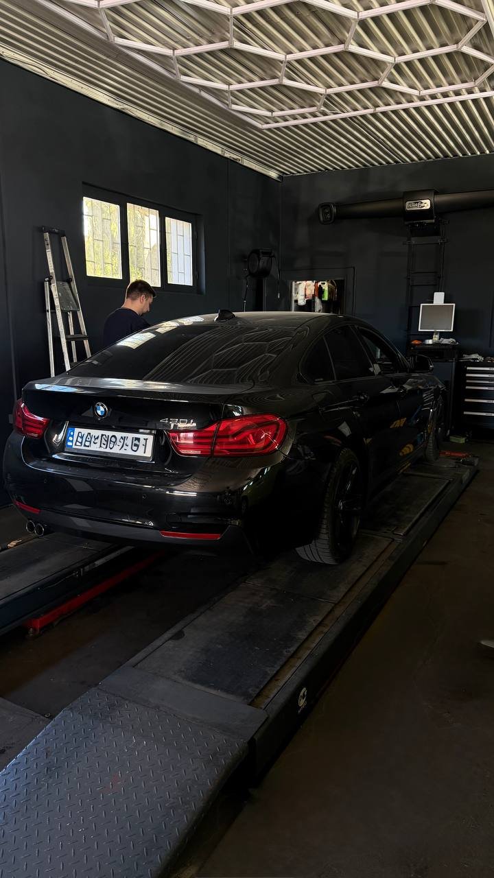 Silver Porsche on lift in garage with neon lighting
