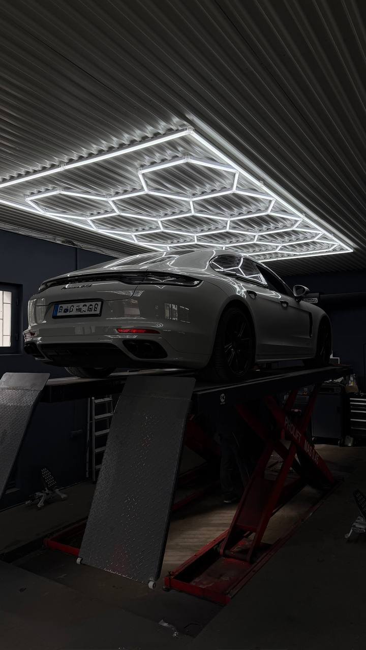 Silver BMW on lift in garage with neon lighting