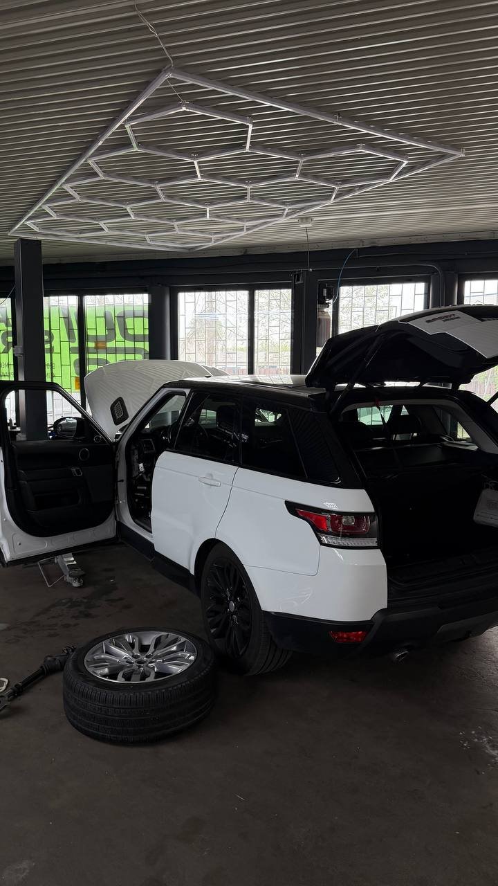 White Range Rover in garage with open doors and neon ceiling