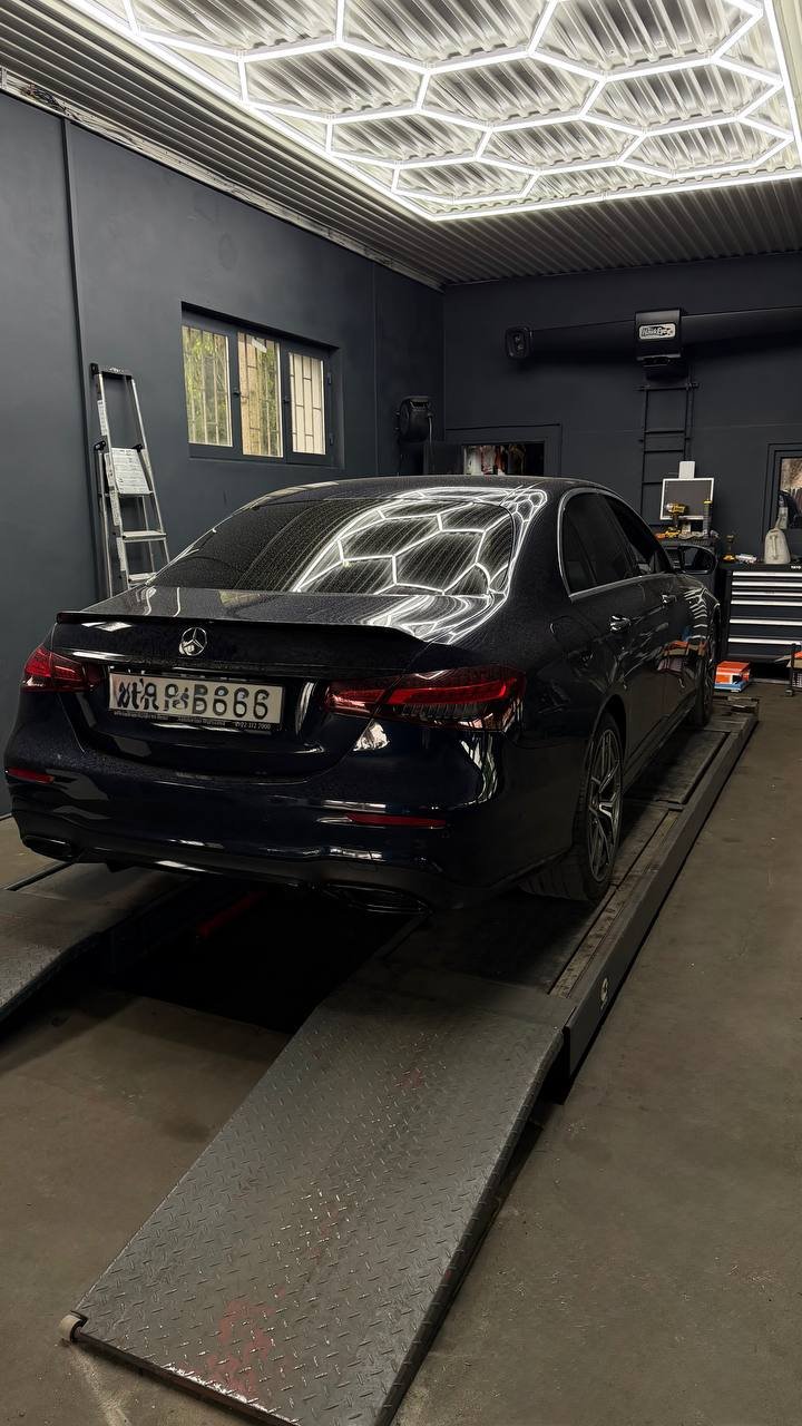 Black car on lift with neon ceiling