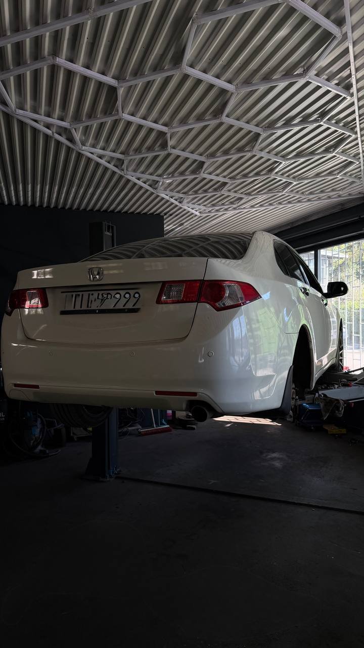 Silver Honda on lift in garage with neon lighting