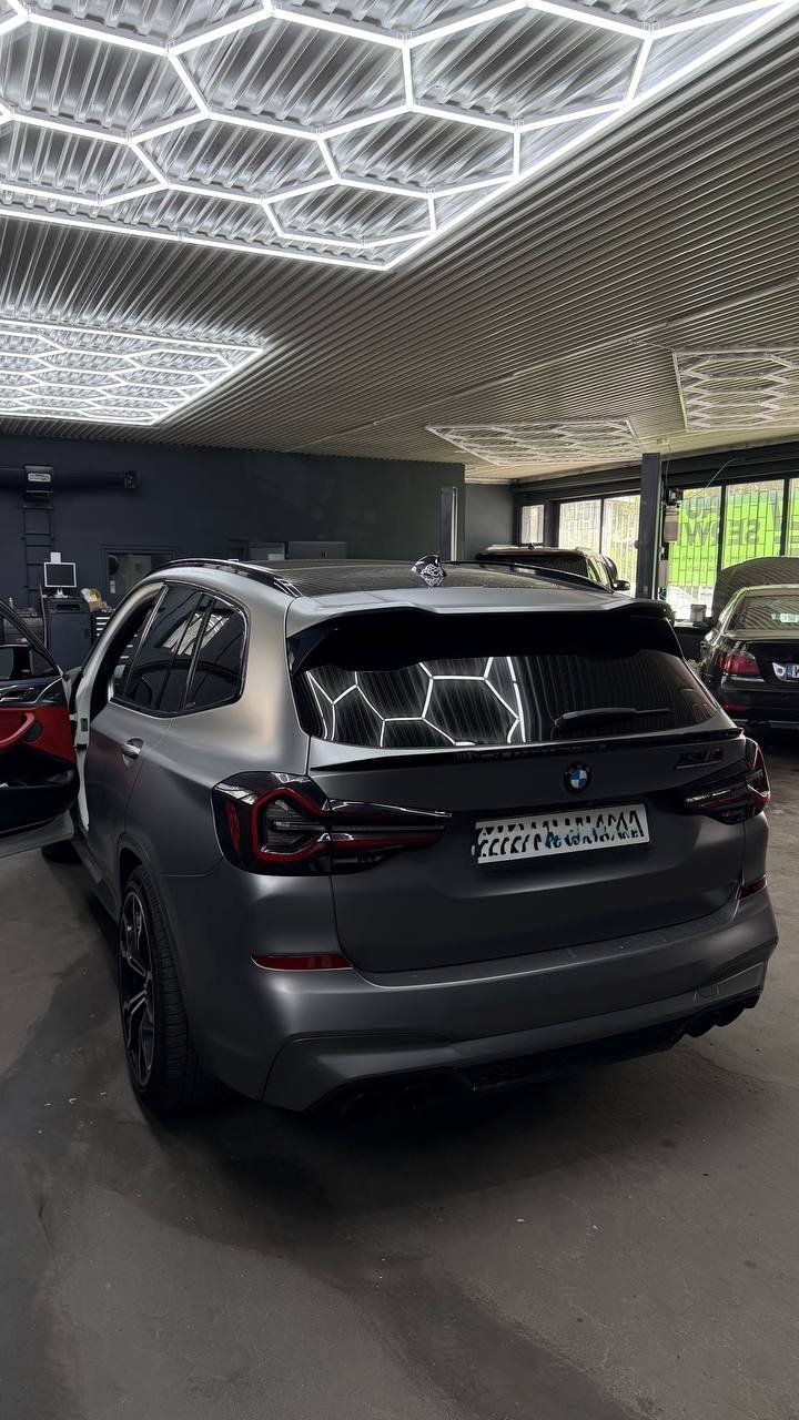 Black BMW on lift in garage with neon lighting