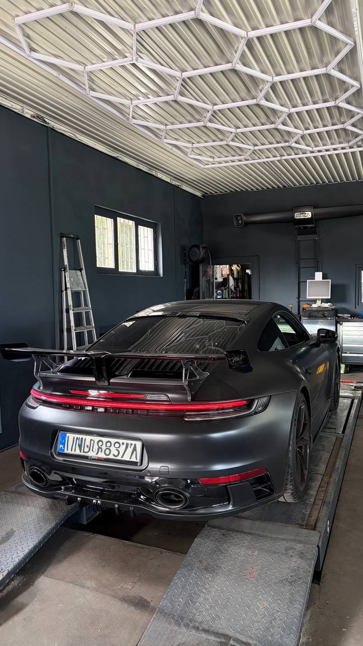 Silver car on lift in garage with metal roof and neon lighting